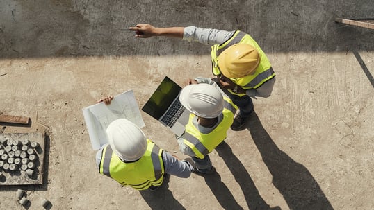 Markets-Engineers-Group-with-Laptop-and-Drawings-on-Construction-Site