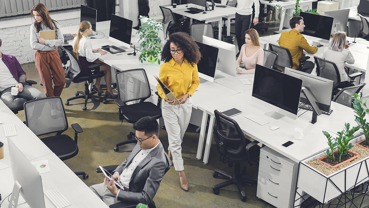 Markets-Office-Several-Workers-At-Desks-with-Young-Woman-Walking